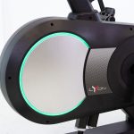 Stationary bike flywheel with a glowing teal ring and Lyon branding on a black frame.