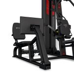 Cable-based multi-station gym machine with leg extension/curl pad and weight stack, black and red frame