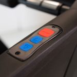 Treadmill control panel with a red Stop button and two blue arrow buttons for incline or speed adjustment, viewed at an angle.