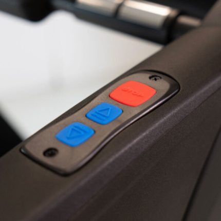 Treadmill control panel with a red Stop button and two blue arrow buttons for incline or speed adjustment, viewed at an angle.