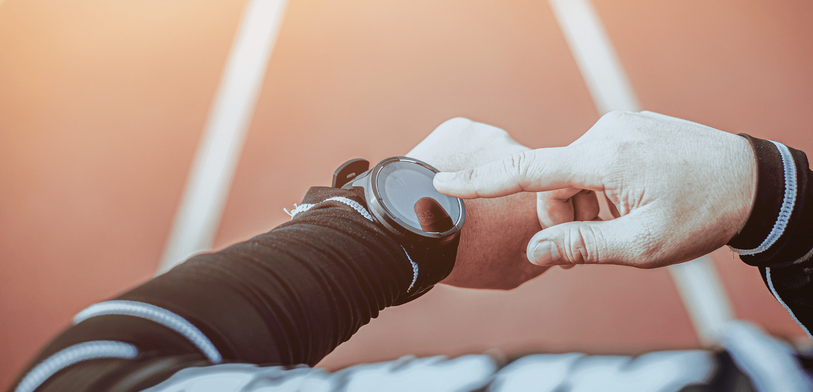Athlete taps their smartwatch on the wrist during a workout on a running track.