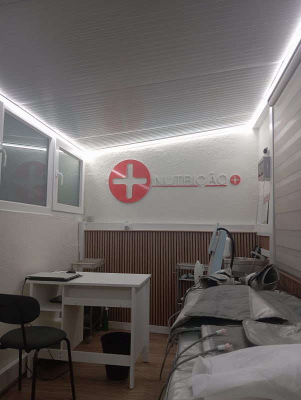 Dental clinic treatment room with a white wall, a patient chair, and a red cross logo reading 'NUTRICAO' on the wall.
