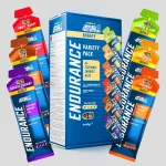 Blue Endurance energy gel box labeled 6x60g surrounded by colorful gel pouches in flavors like Fruit Burst, Cola, Blackcurrant, Lemon & Lime, Tropical, and Orange.
