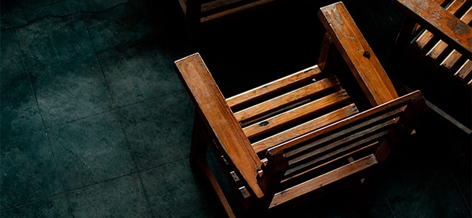 Top-down view of a wooden chair on a dark teal tiled floor.