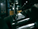 Industrial conveyor with metal rollers in a dim factory, moving along a dark line.