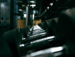 Close-up of shiny metal roller components in a dark industrial machine, shallow depth of field and blurred background.